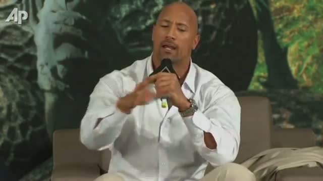 Watch The Rock Sings, Flexes Pecs, Charms Press Video